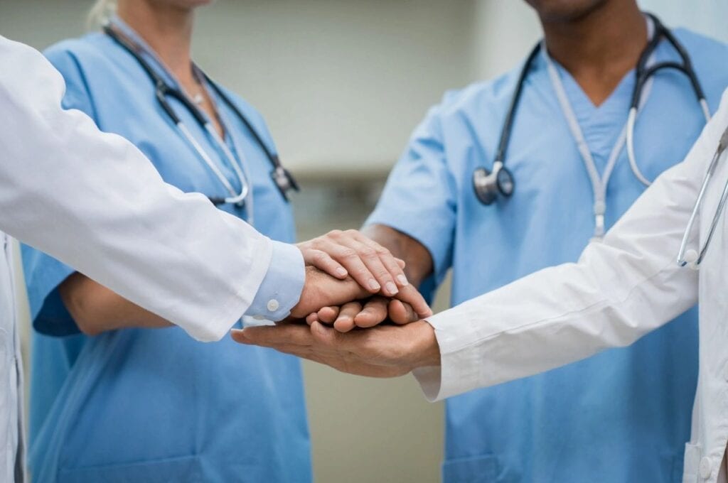 Two doctors holding hands with one doctor wearing a white shirt.